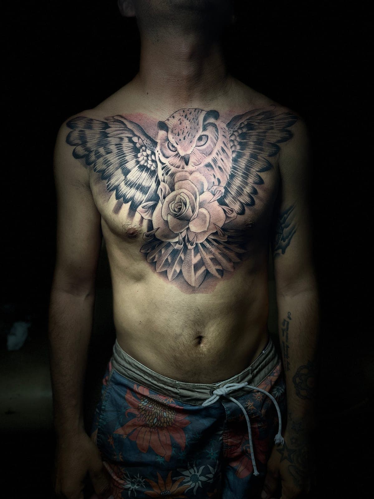 Búho con las alas abiertas y una rosa en el centro, tatuado en el pecho en black and grey de lado a lado