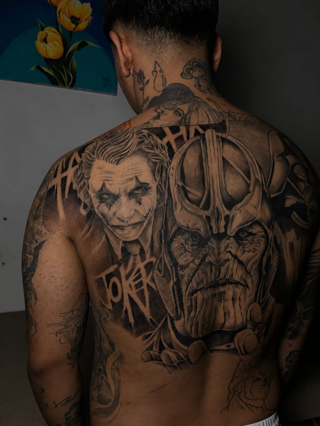 Espalda completa en realismo black and grey con el Joker y Thanos, terminada, con lettering integrado entre las dos figuras